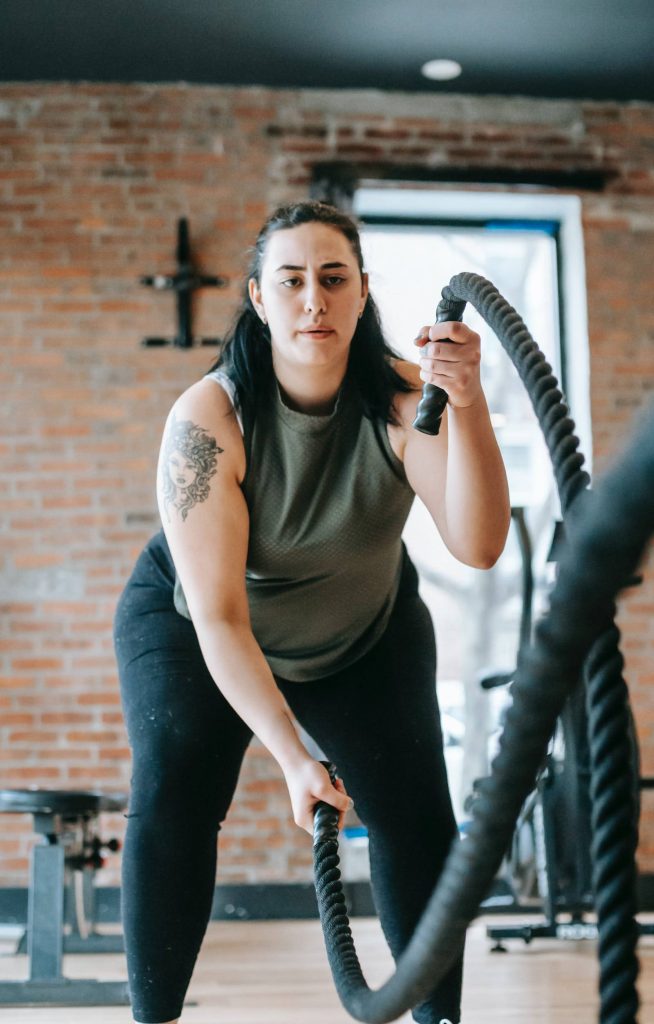 Determined athlete training with battle ropes in industrial gym workout motivation wallpaper