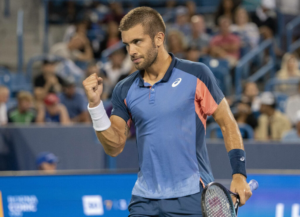 Determined Borna Coric clenches fist in victory dynamic blue tennis match high resolution wallpaper