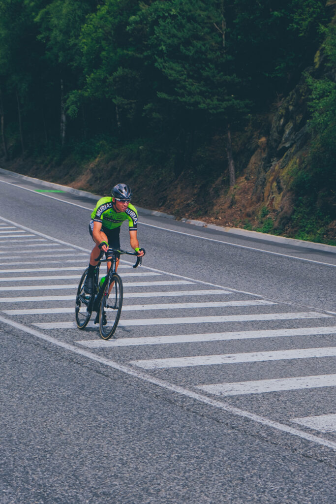 Determined cyclist riding fast on tree-lined country road vibrant outdoor adventure wallpaper background