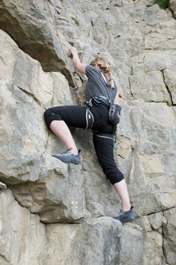 Determined female climber ascending rugged rock face showing strength and focus in sport climbing Wallpaper
