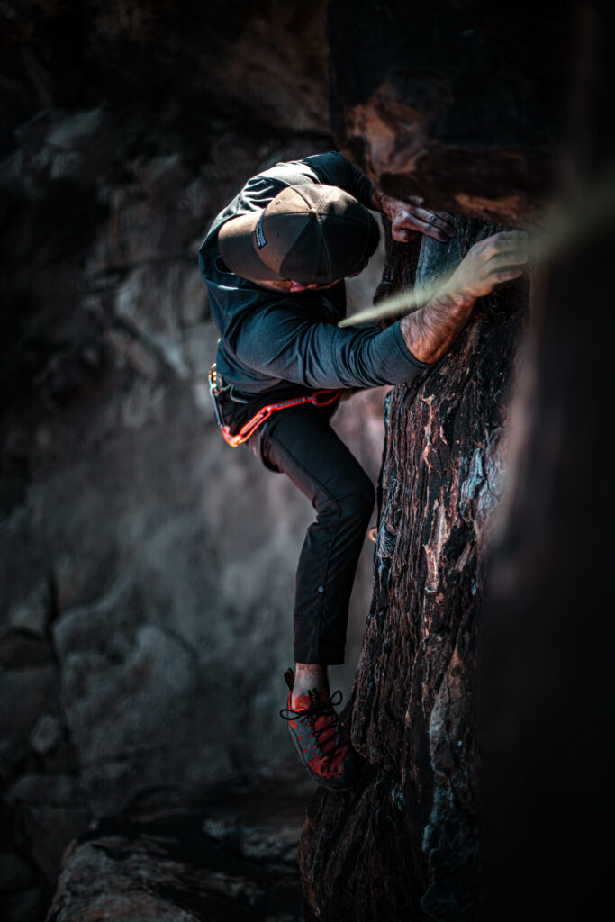 Man climbing rugged dark rock wall demonstrating determination adventure dynamic outdoor sport Wallpaper