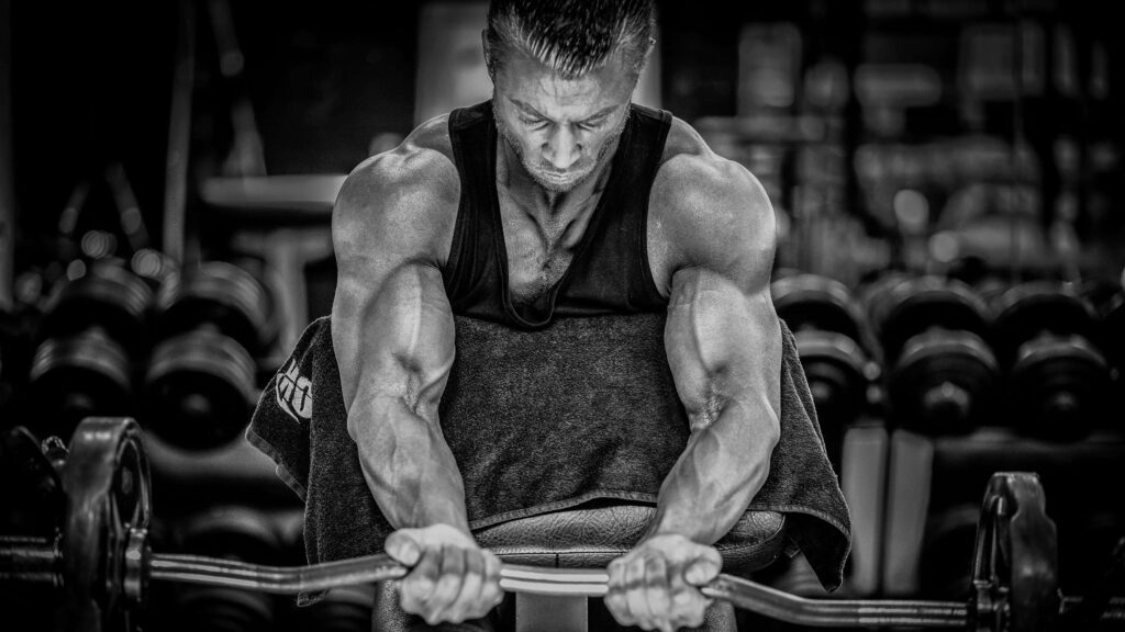 Determined man lifting weights intensely in gym pushing limits strength motivation wallpaper
