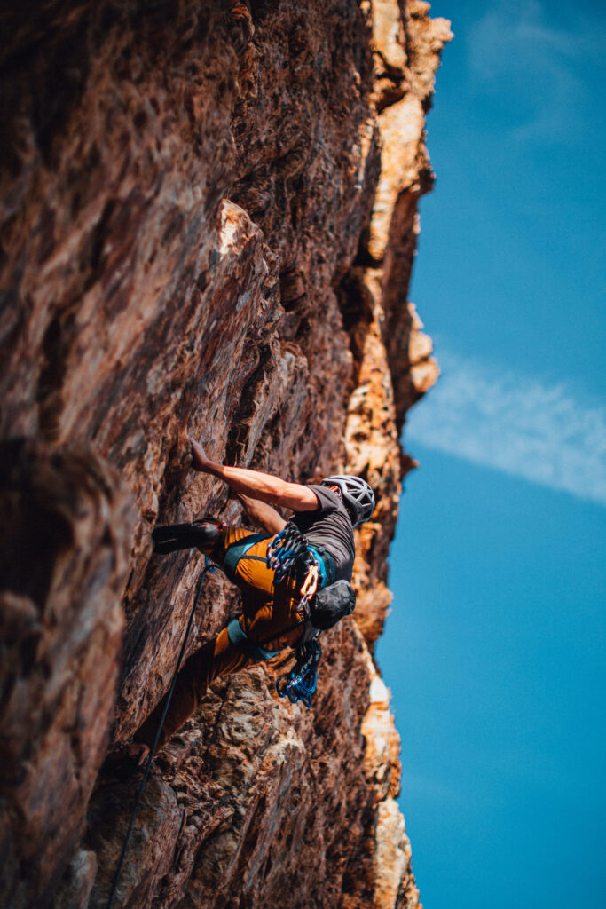 Determined man rock climbing rugged cliff with vivid blue sky adventure wallpaper background