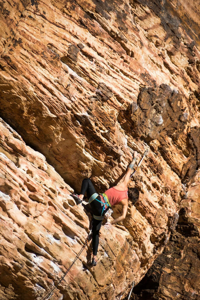 Determined man rock climbing steep rugged rock face showcasing strength and focus wallpaper