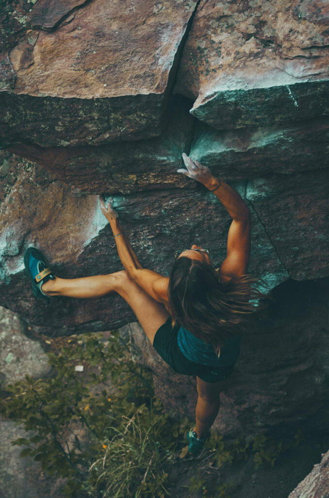 Determined sport woman climbing rugged mountain rock face showing strength and focus outdoors Wallpaper