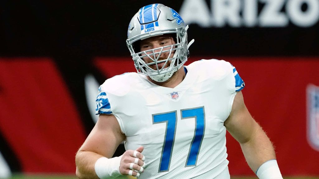 Detroit Lions center Frank Ragnow in white uniform number 77 focused during intense football action Wallpaper