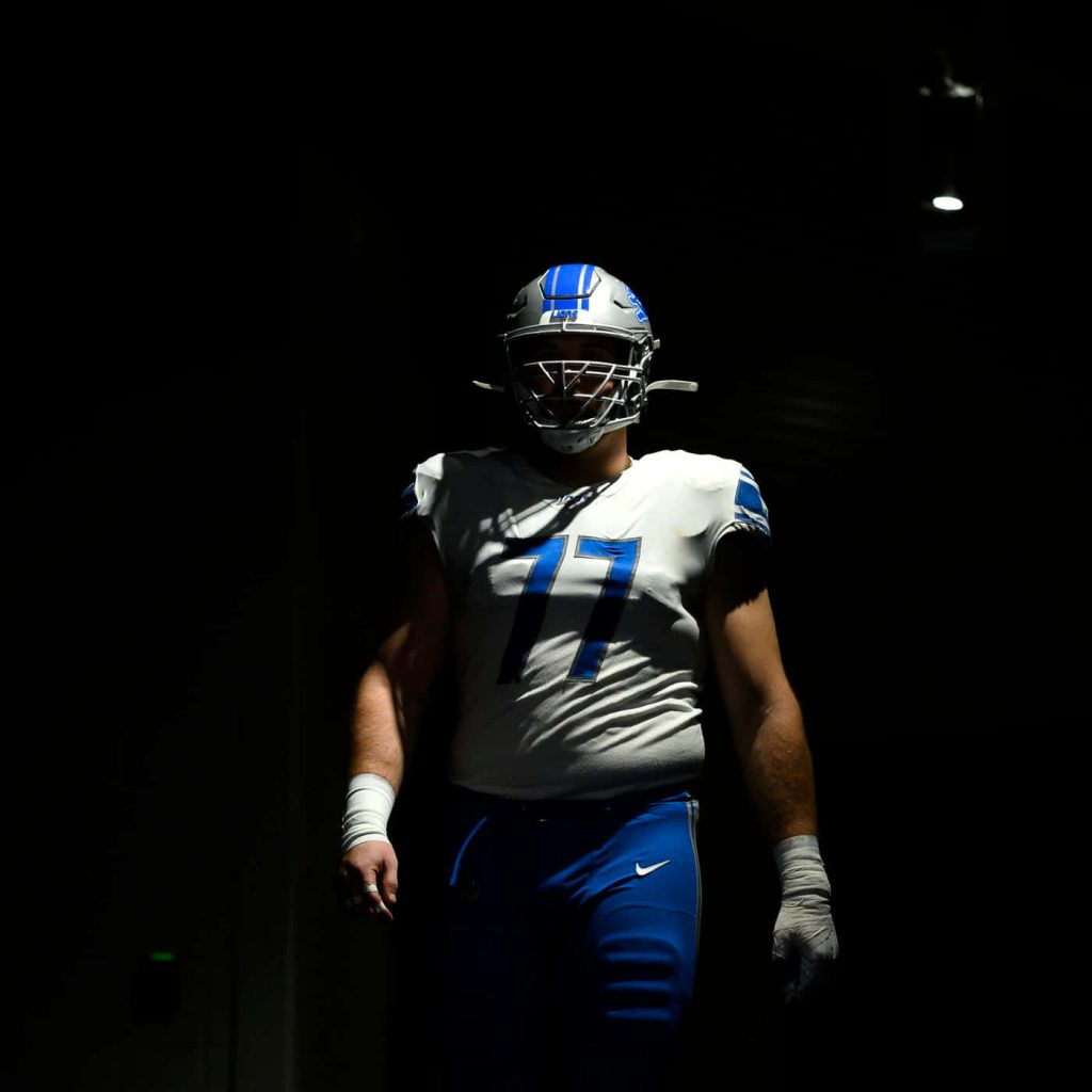 Detroit Lions center Frank Ragnow in white 77 uniform spotlighted dramatic sports wallpaper