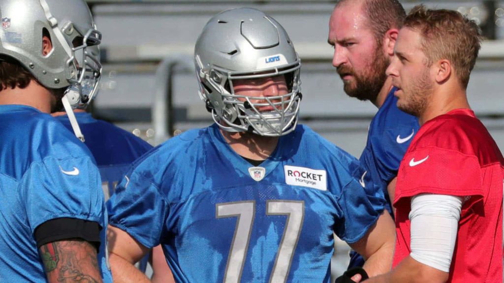Detroit Lions quarterback Jared Goff in red and center Frank Ragnow in blue training outdoors wallpaper