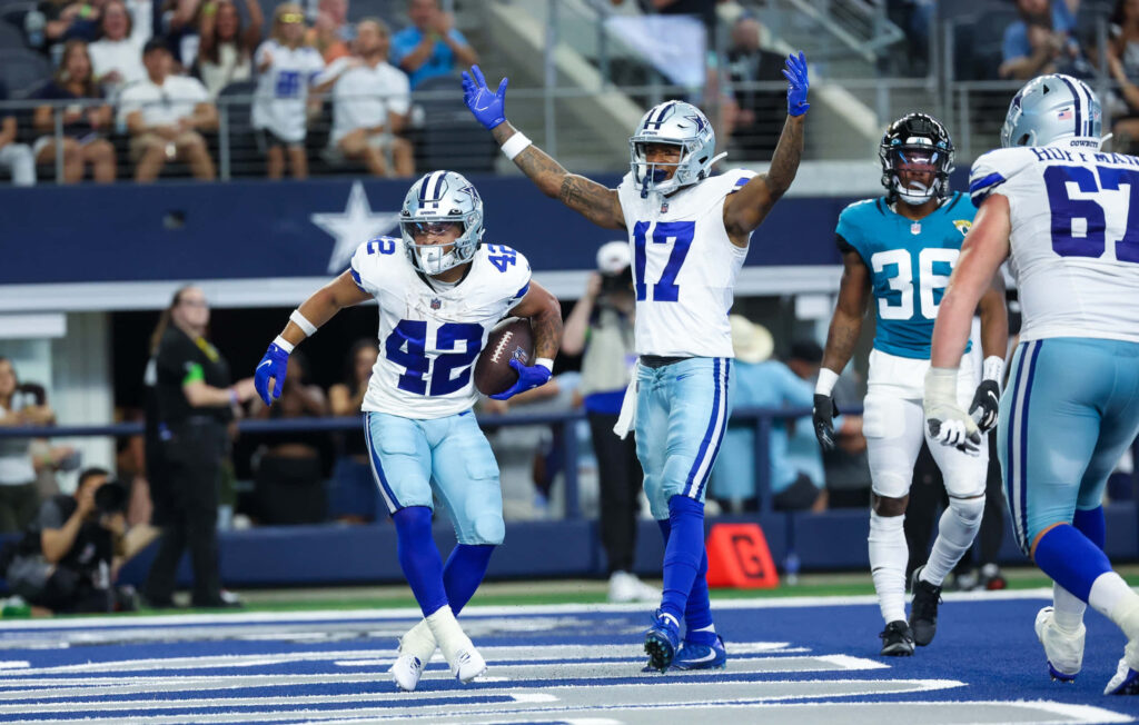 Dallas Cowboys running back Deuce Vaughn scores touchdown on vibrant blue white field with teammates Wallpaper