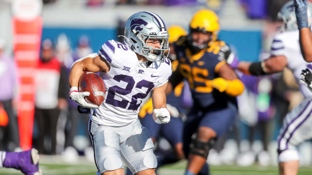 Deuce Vaughn Kansas State Wildcats football player sprinting with intense focus in stadium action Wallpaper