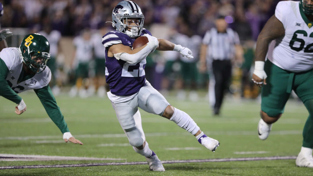 Deuce Vaughn sprinting in Kansas State uniform against Baylor defenders bright stadium lights Wallpaper