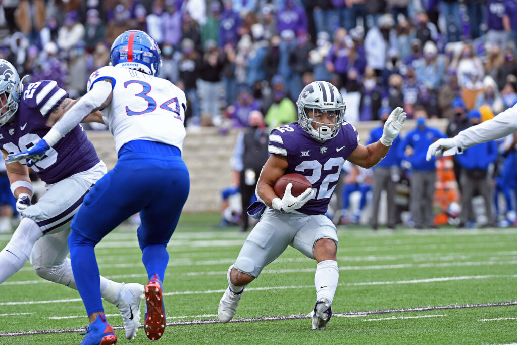 Deuce Vaughn in purple Kansas State uniform running during intense college football game action wallpaper