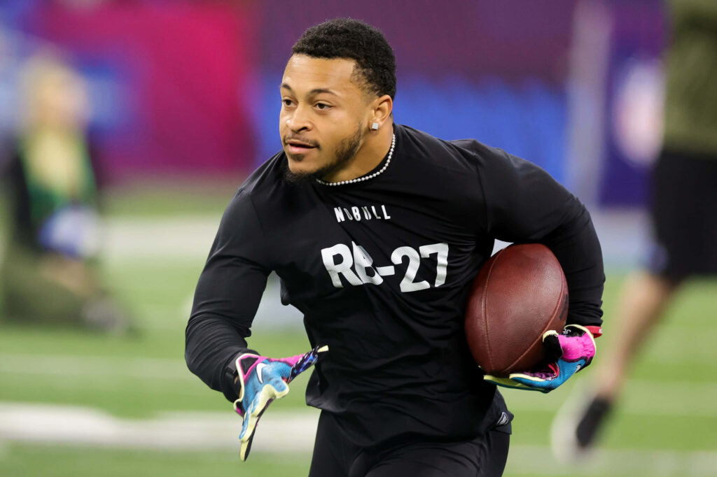 Deuce Vaughn sprinting in football gear during intense training drill showcasing agility and focus Wallpaper