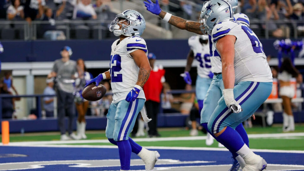 Deuce Vaughn celebrates Dallas Cowboys touchdown with vibrant uniform and energetic stadium fans Wallpaper