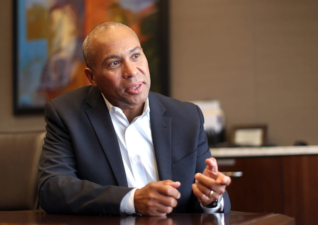 Deval Patrick speaking with expressive gestures in modern office with abstract art and warm light Wallpaper