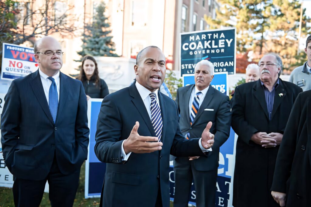 Deval Patrick speaking at outdoor political rally with diverse crowd and colorful campaign signs Wallpaper