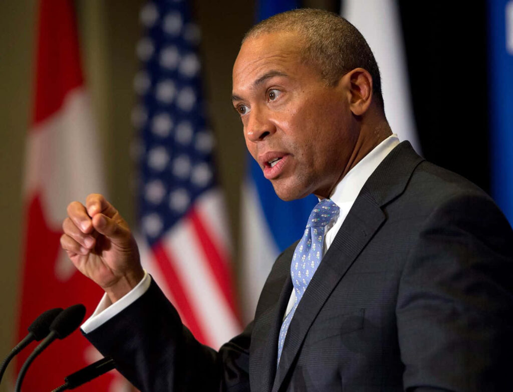 Deval Patrick sincere portrait in formal suit speaking with US Canadian flags leadership wallpaper