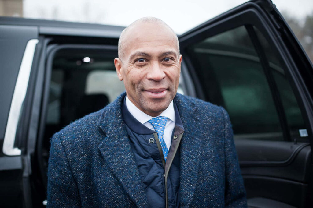 Former Massachusetts Governor Deval Patrick stepping out of vehicle in blue suit and textured coat Wallpaper