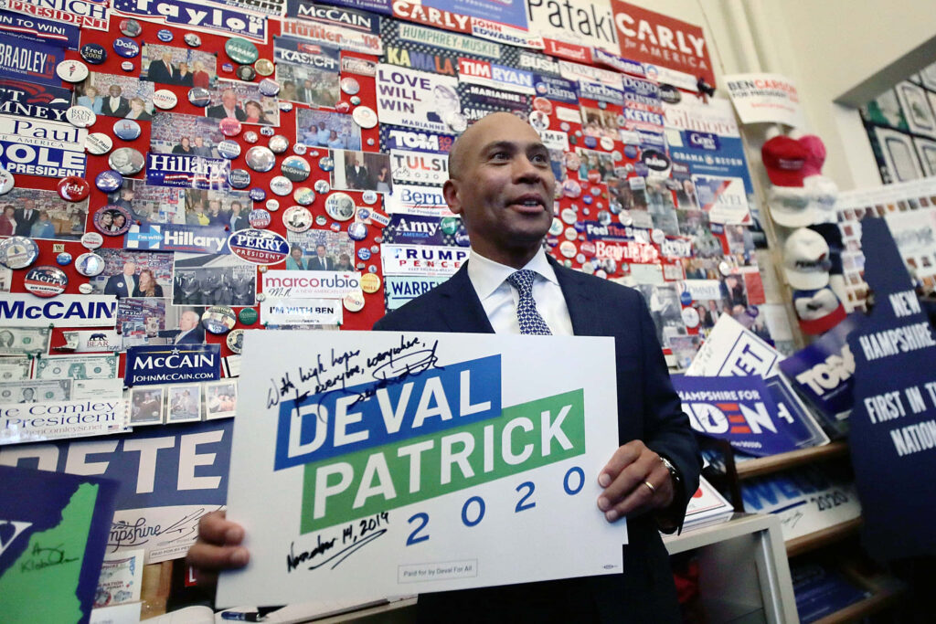 Deval Patrick signing 2020 campaign banner surrounded by vibrant political memorabilia and buttons Wallpaper
