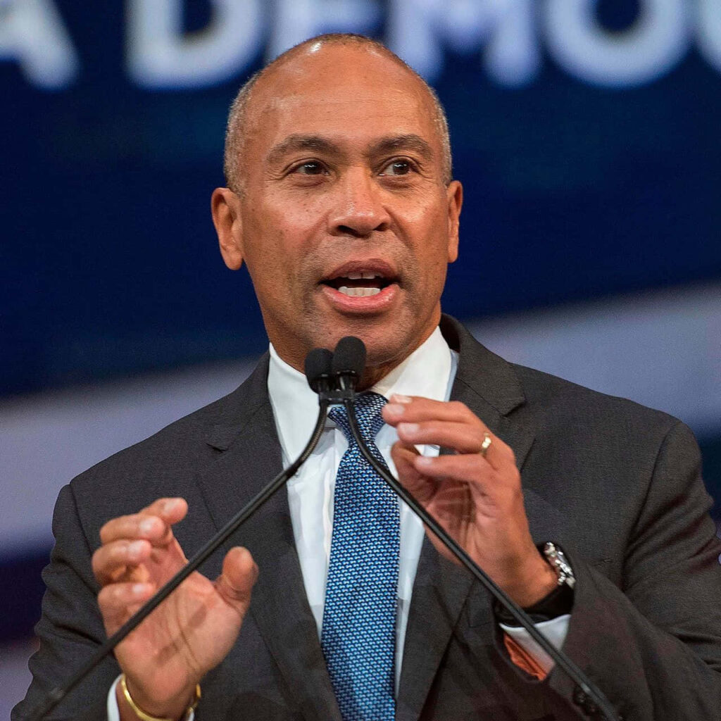 Deval Patrick speaking passionately on stage in formal suit with blue background and focused lighting Wallpaper