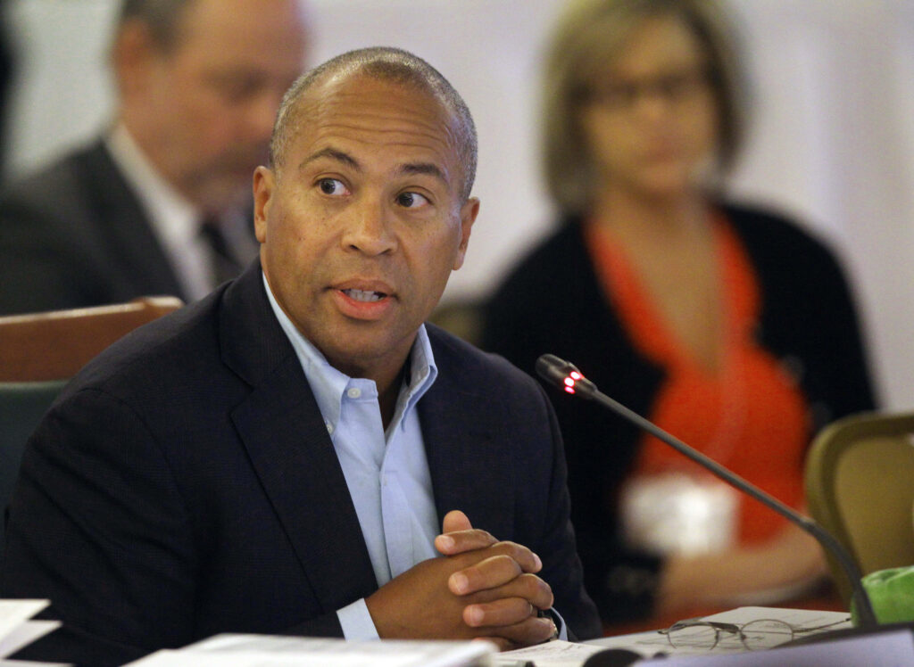 Deval Patrick speaking at formal meeting with microphone in professional warm-lit setting Wallpaper