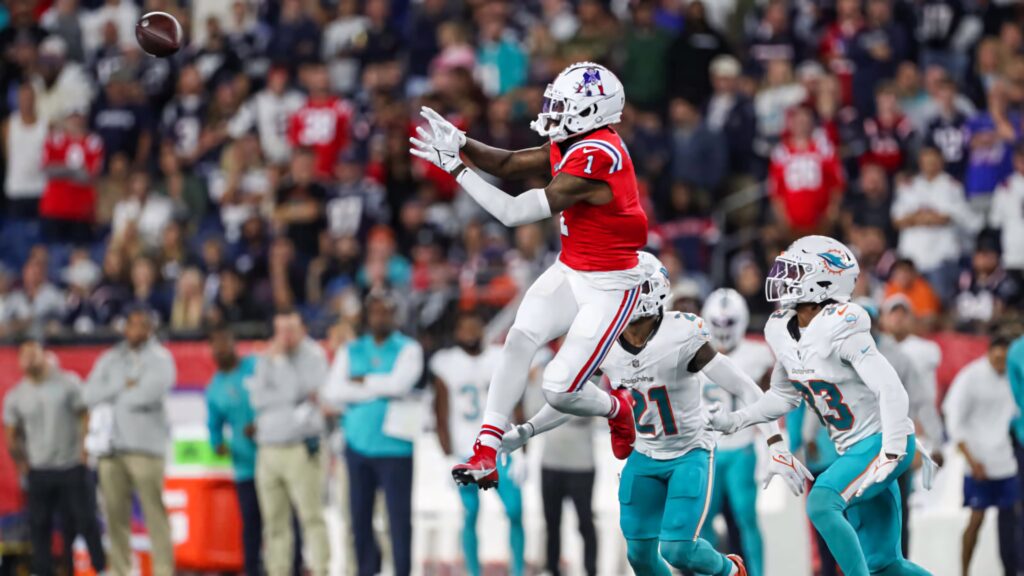 Devante Parker jumps high to catch a football during an intense professional football game action shot Wallpaper
