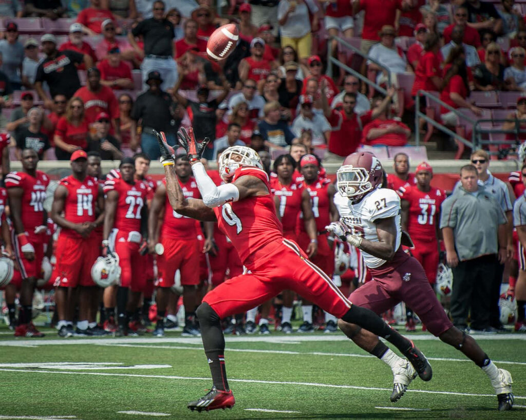 Devante Parker catching football in red uniform with defender and packed stadium background Wallpaper