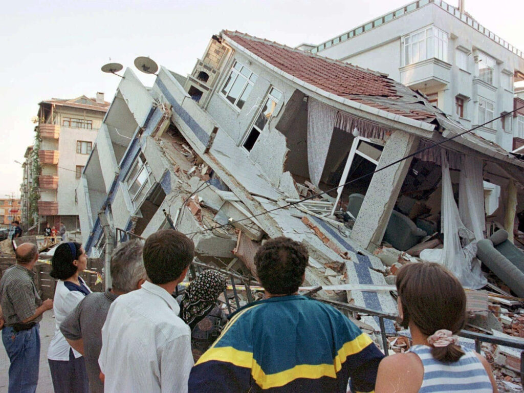 People observing collapsed multi-story building debris showcasing earthquake damage wallpaper background