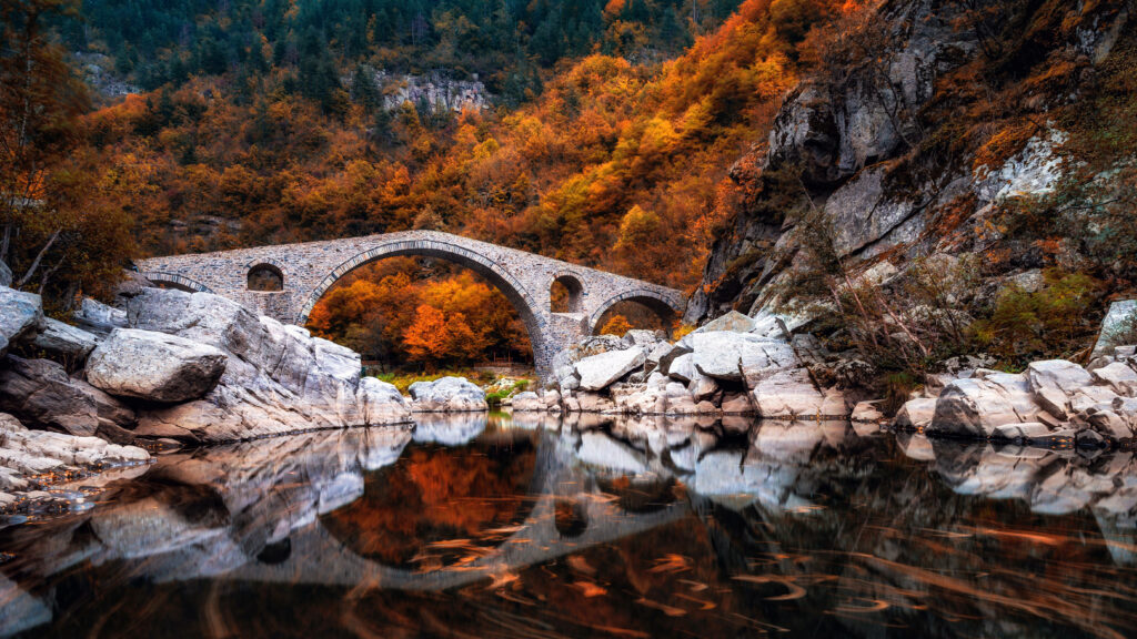 Devils Bridge Bulgaria surrounded by colorful autumn trees reflected in calm clear river wallpaper
