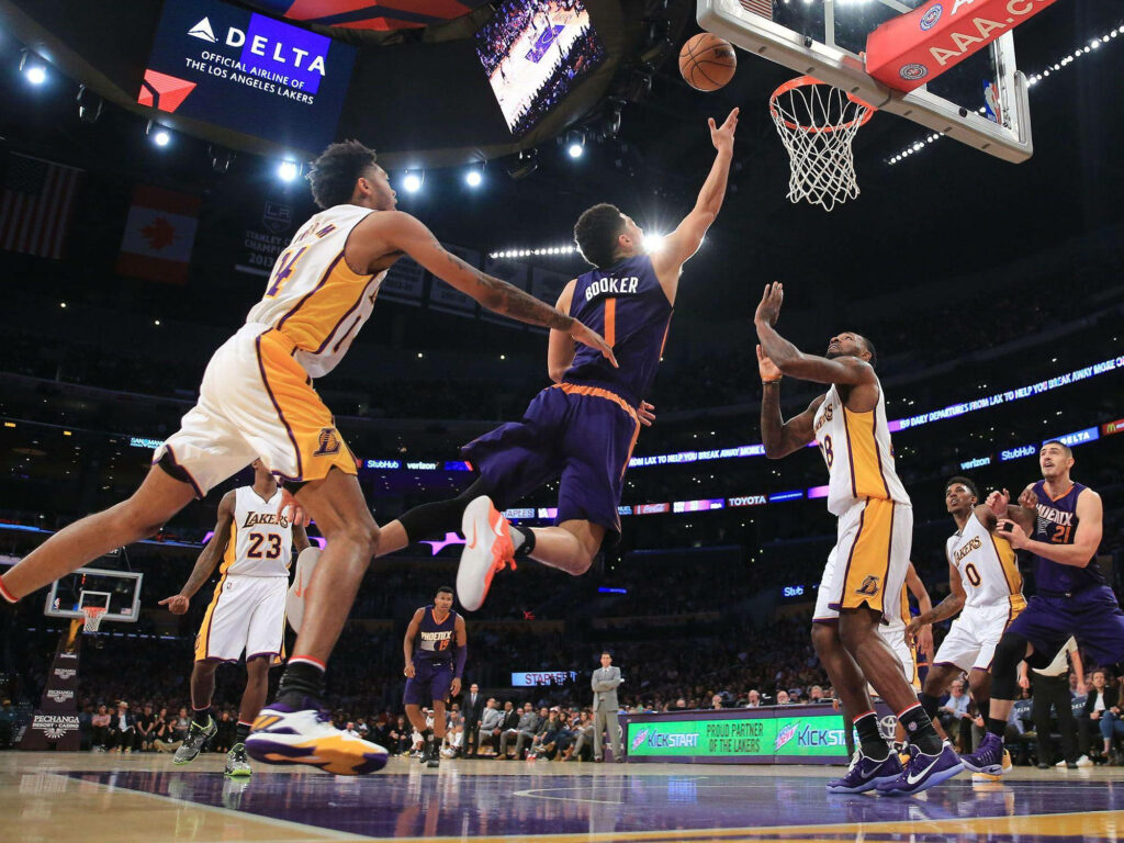 Devin Booker midair layup against Lakers defenders bright NBA arena lights action wallpaper