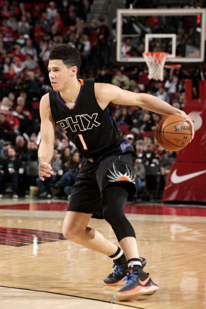 Devin Booker dribbling basketball in black PHX jersey vibrant arena action shot wallpaper background
