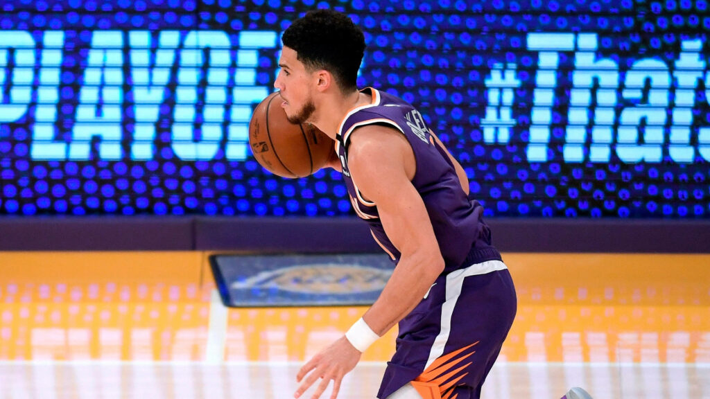 Devin Booker dribbling in Phoenix Suns purple jersey during intense basketball playoff game action Wallpaper
