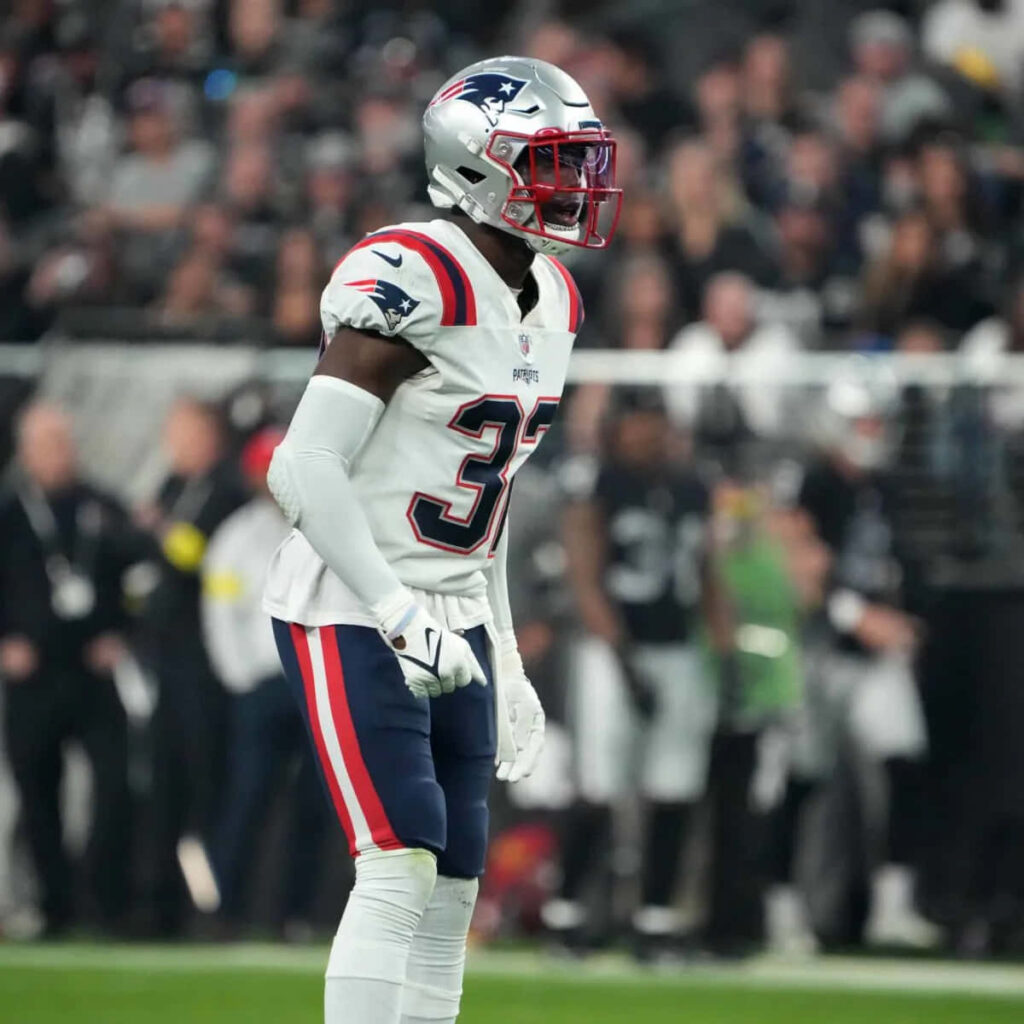 Devin McCourty in New England Patriots uniform focused on field with vibrant stadium crowd background Wallpaper