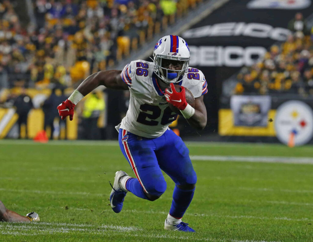 Devin Singletary running for Buffalo Bills on vibrant football field with crowd and game action Wallpaper