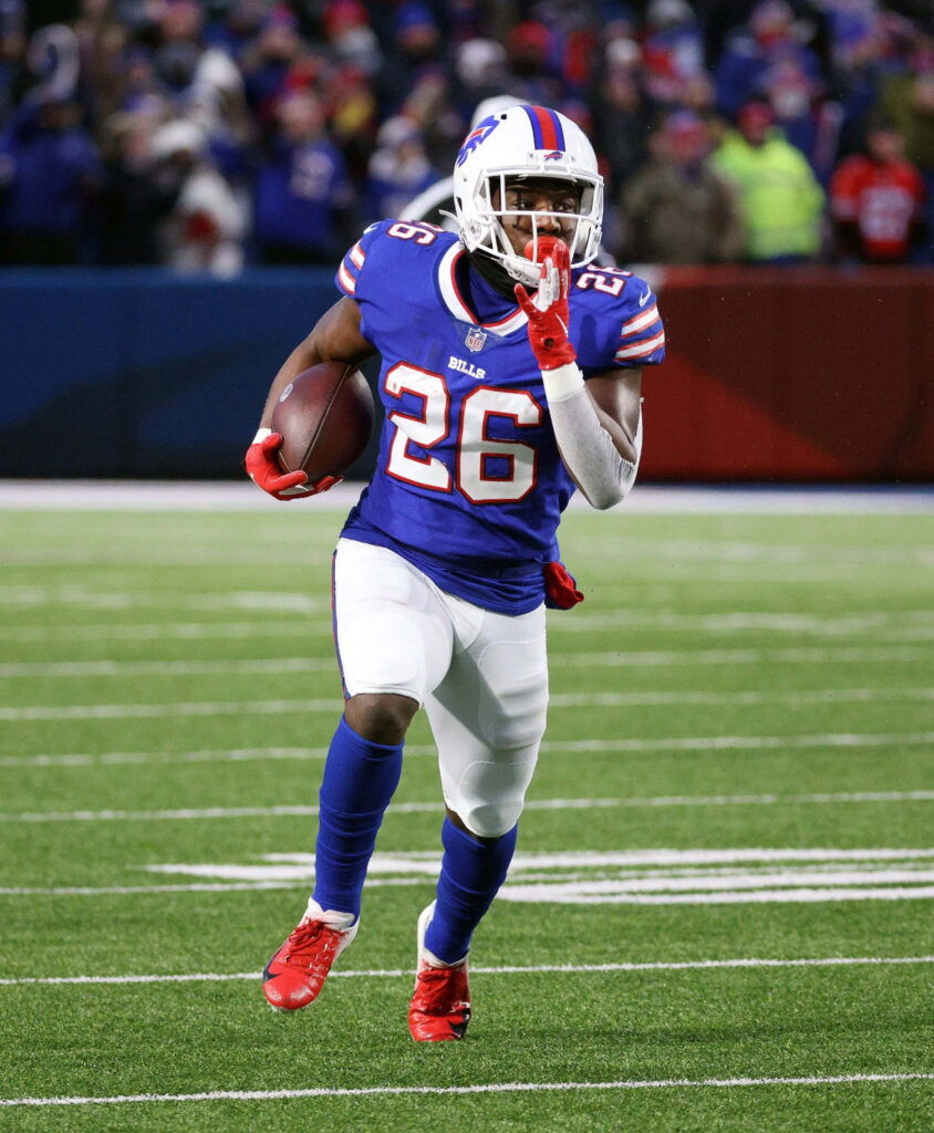 Devin Singletary Buffalo Bills sprinting with football in blue red uniform on lit field wallpaper