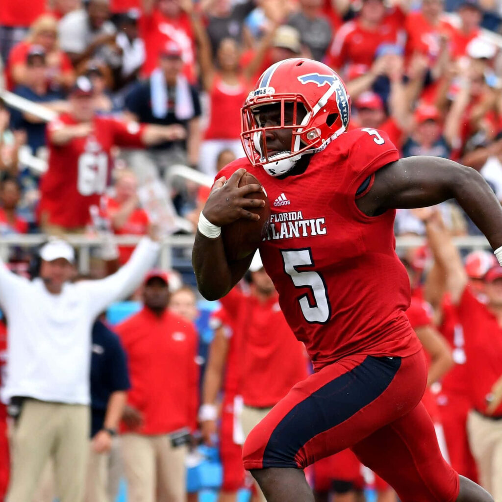 Devin Singletary in Florida Atlantic University uniform charging down the football field crowd background Wallpaper