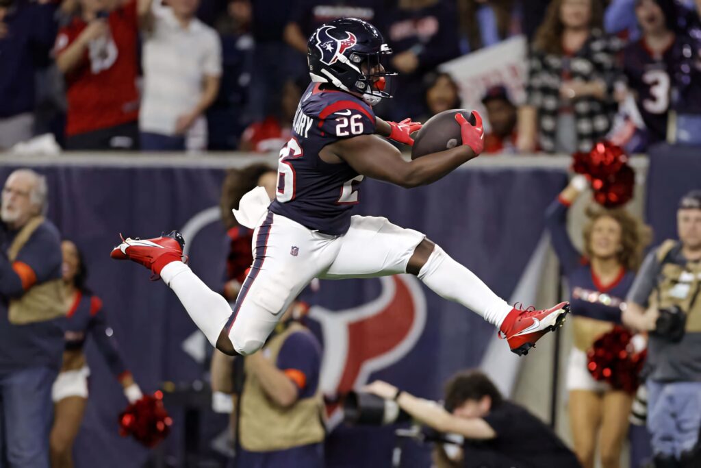 Devin Singletary Houston Texans leaping airborne celebrating football catch in vibrant stadium crowd Wallpaper