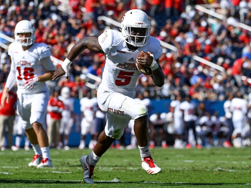 Devin Singletary sprinting with football in white uniform during intense vibrant stadium game action Wallpaper