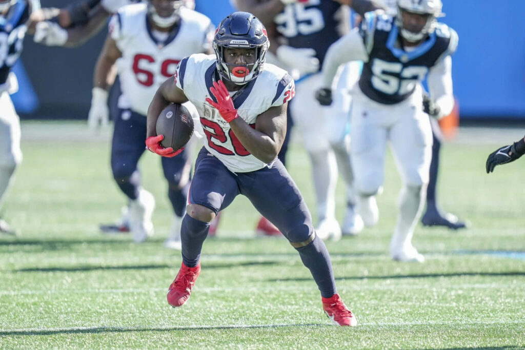 Devin Singletary sprinting with intense focus in vibrant football game wallpaper background