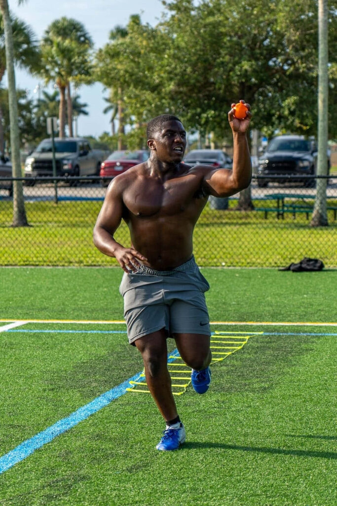 Devin Singletary training outdoors on vibrant football field with clear skies and palm trees Wallpaper