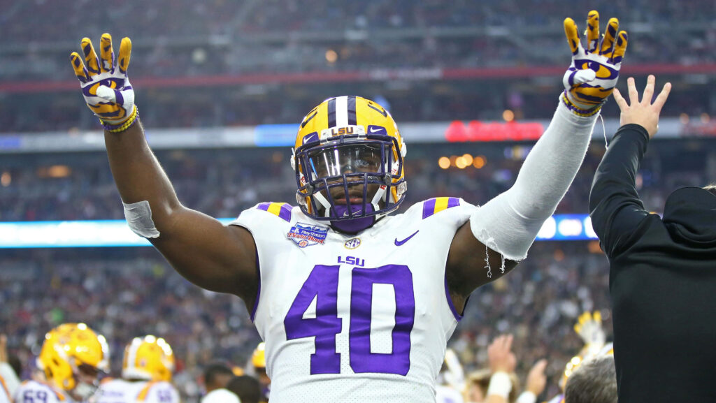LSU football Devin White number 40 celebrating victory in gold and purple uniform stadium background Wallpaper