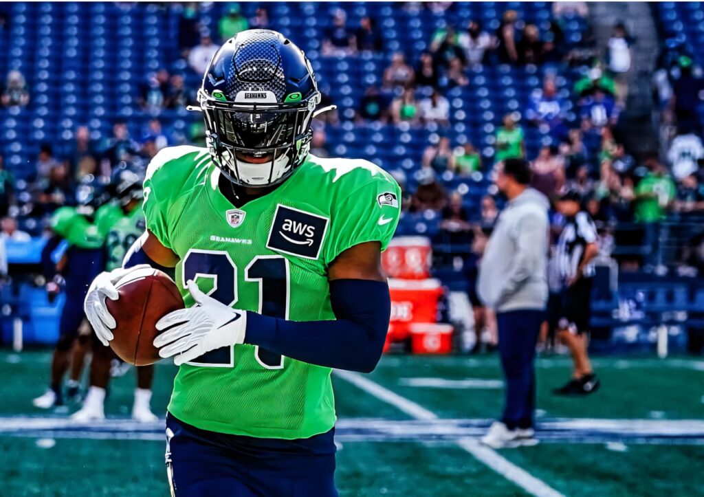 Devon Witherspoon in green jersey 21 poised on football field showing focus and athletic power Wallpaper