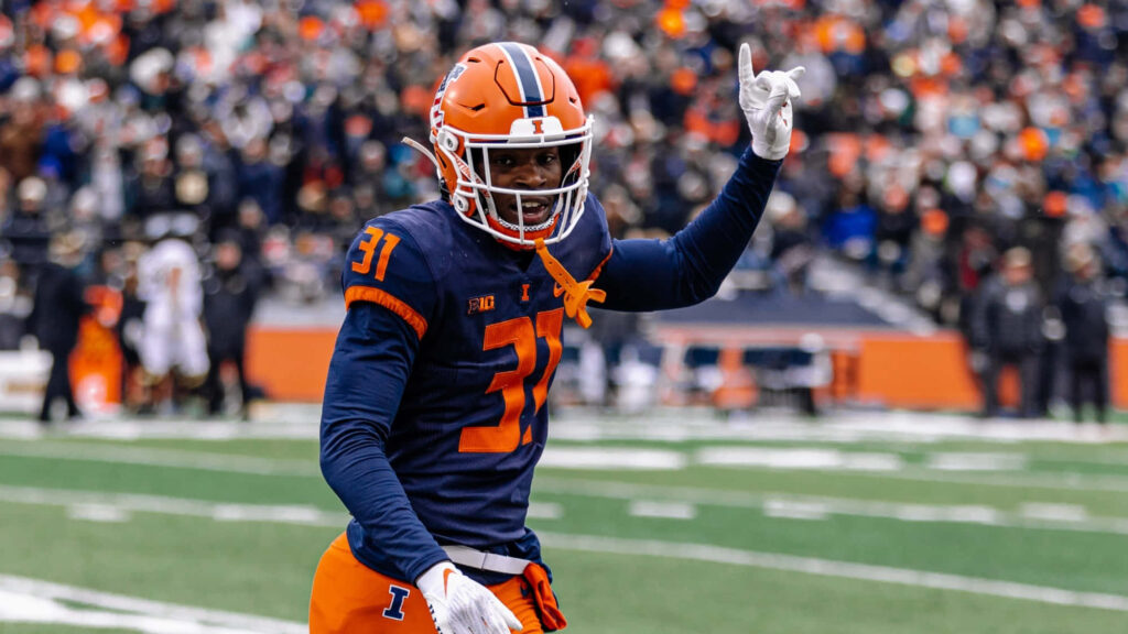 Illinois Football Devon Witherspoon celebrates victory in navy orange uniform on game day field Wallpaper