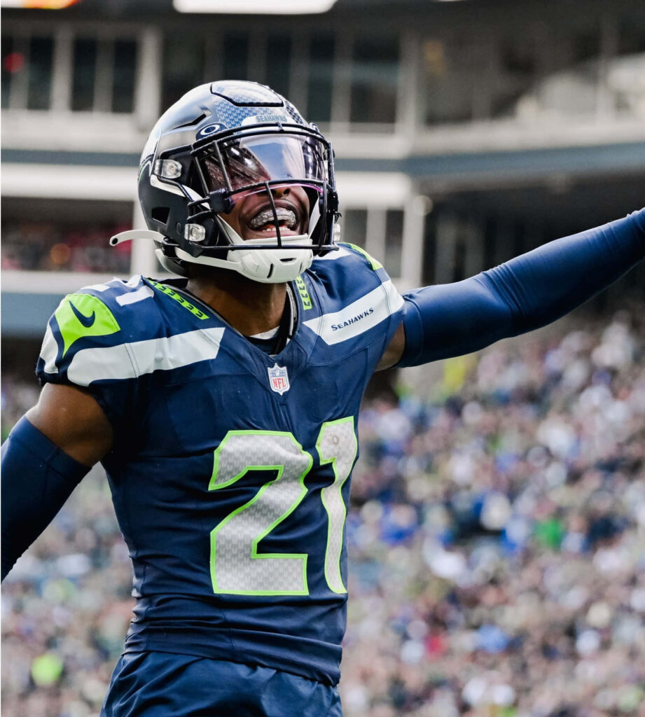 Devon Witherspoon Seahawks wallpaper celebrating on field in vibrant blue and green NFL game day