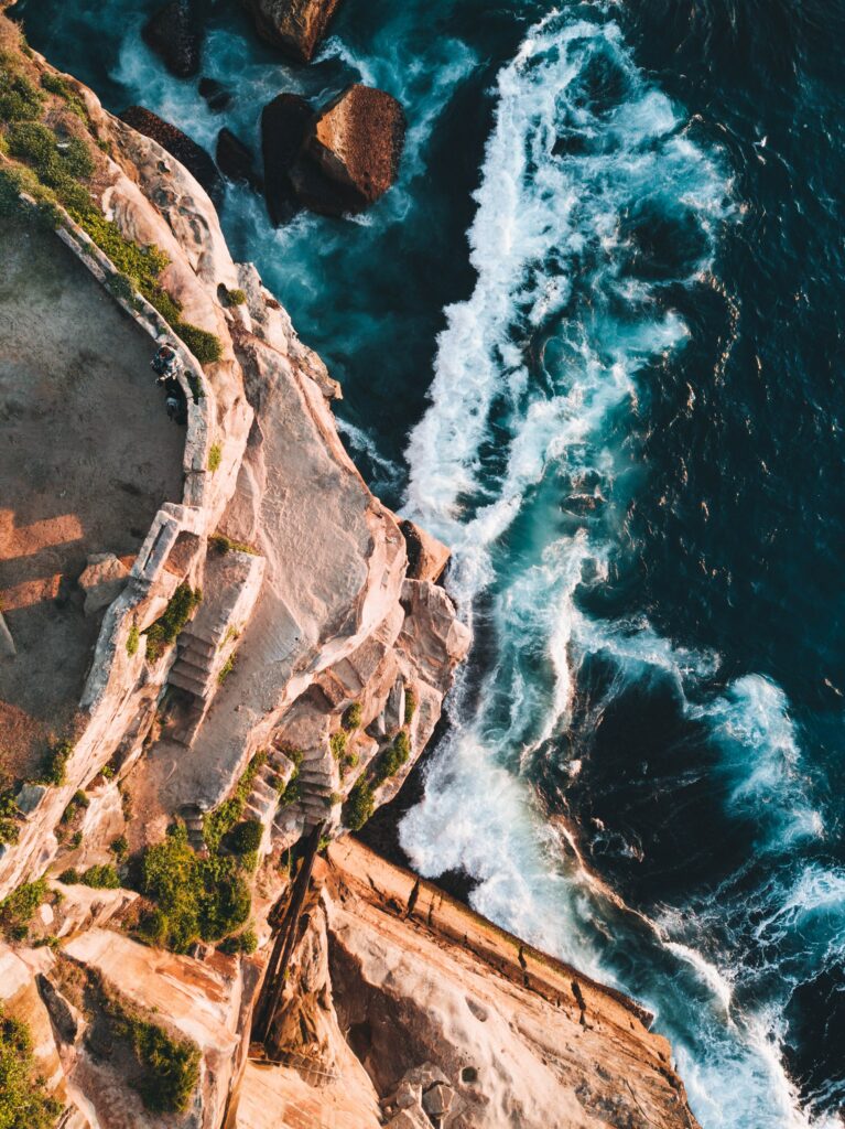Aerial view of Diamond Bay Reserve cliffs and turquoise surf in Vaucluse Australia wallpaper background