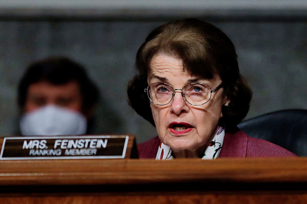 Dianne Feinstein at government hearing with focused expression and official nameplate wallpaper background