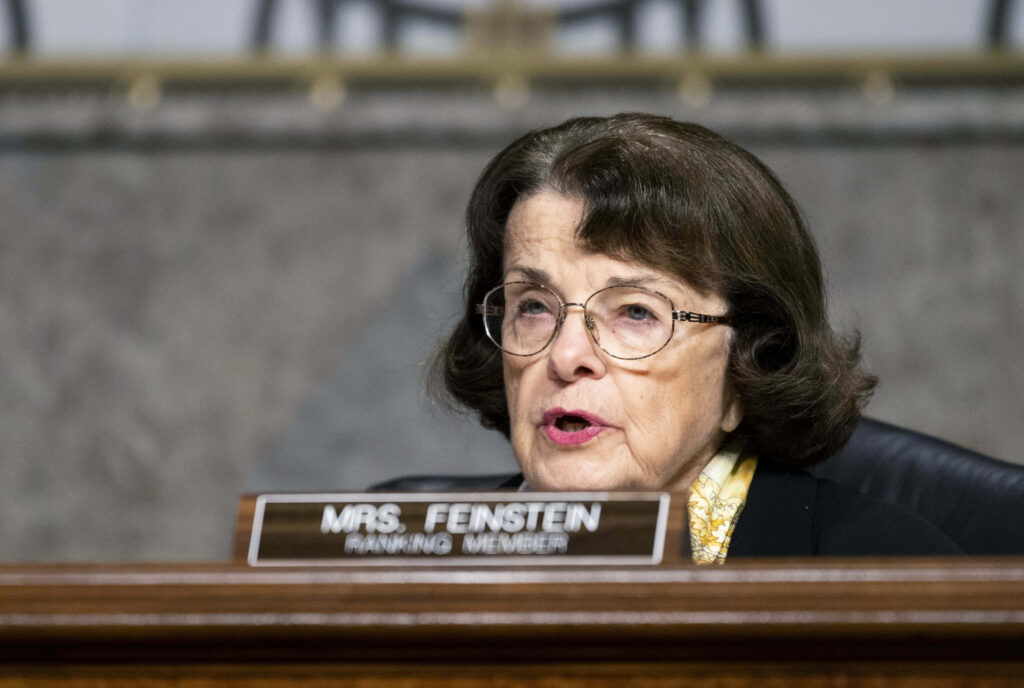 Dianne Feinstein sitting behind Mrs Feinstein Ranking Member nameplate in formal government setting Wallpaper