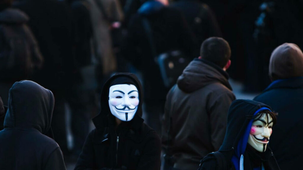 The Enigmatic Duo: Hooded Figures Blend In Amidst Crowd in 4K Hacker Background Wallpaper