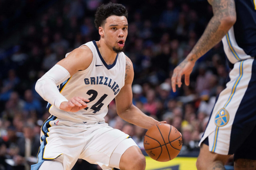 Dillon Brooks driving past defenders in Grizzlies uniform during intense basketball game action Wallpaper