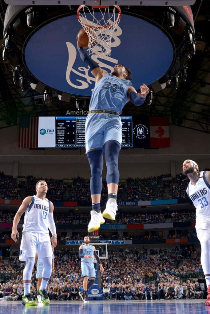 Dillon Brooks soaring for a dunk intense basketball action vibrant arena crowded stadium background Wallpaper